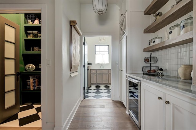 interior space featuring light stone countertops, pendant lighting, white cabinetry, wine cooler, and dark hardwood / wood-style floors