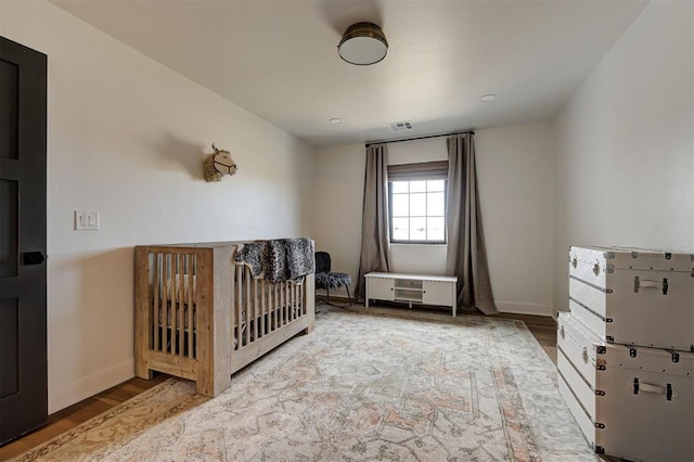 bedroom with hardwood / wood-style floors and a nursery area