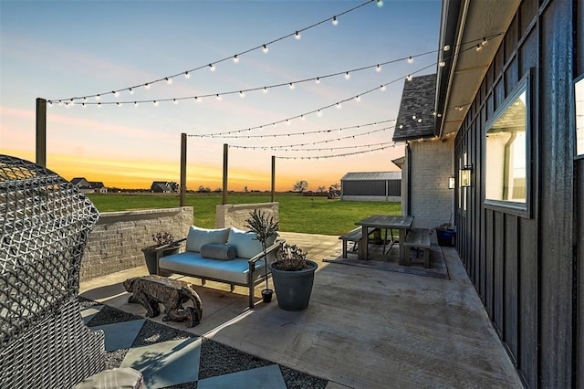 patio terrace at dusk with outdoor lounge area and a lawn