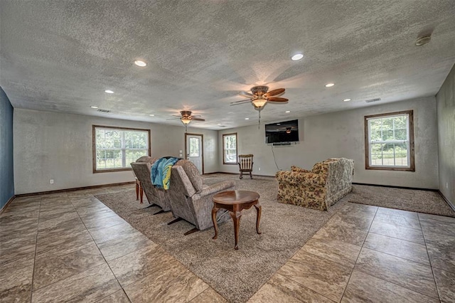 living room with ceiling fan, plenty of natural light, and a textured ceiling