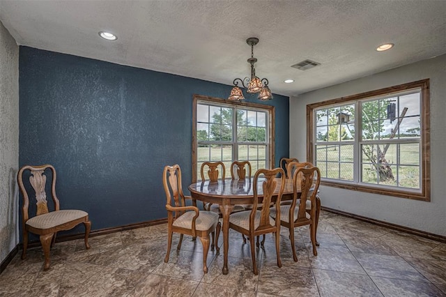 dining space with a textured ceiling and a notable chandelier