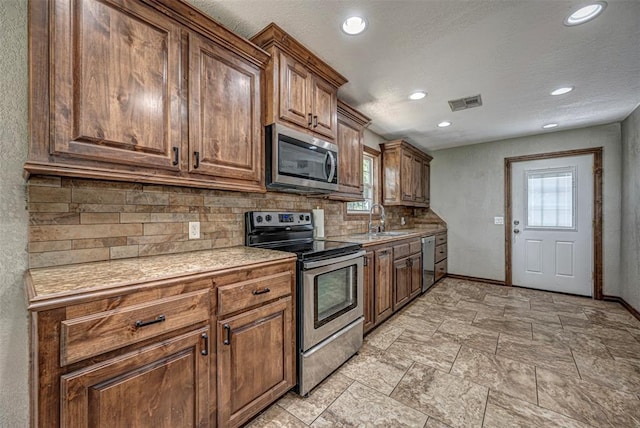 kitchen with appliances with stainless steel finishes, tasteful backsplash, plenty of natural light, and sink