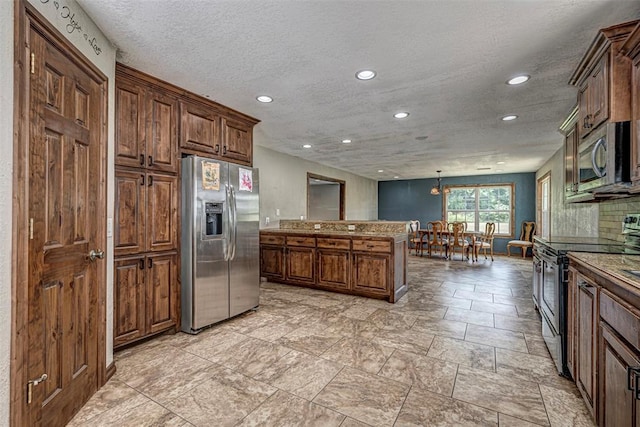 kitchen featuring a center island, light stone counters, a textured ceiling, decorative light fixtures, and appliances with stainless steel finishes