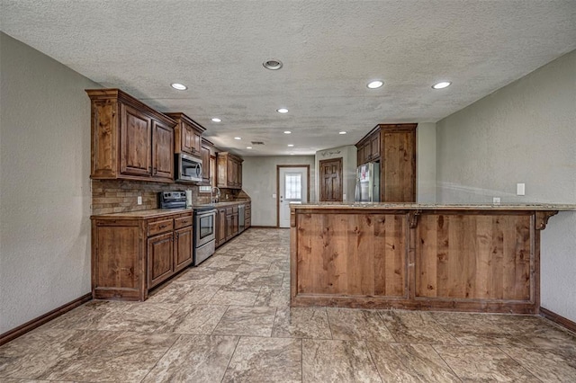 kitchen with sink, stainless steel appliances, kitchen peninsula, a kitchen bar, and decorative backsplash