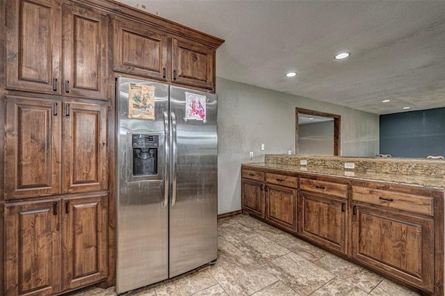 kitchen featuring stainless steel fridge and light stone counters