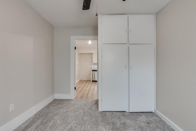 unfurnished bedroom with light carpet, a closet, and ceiling fan