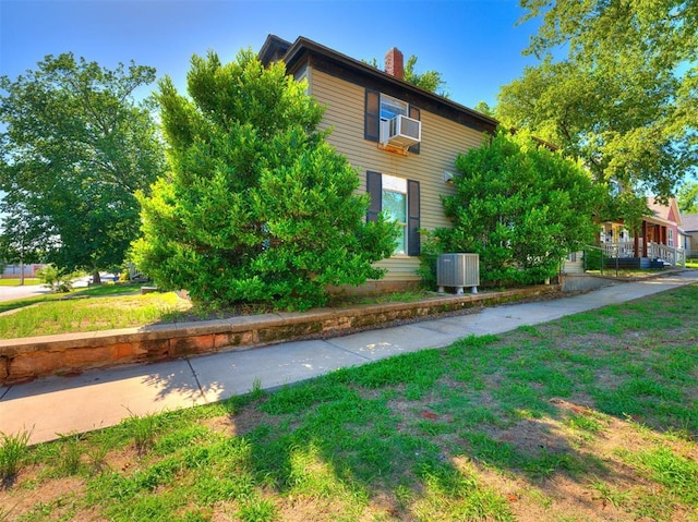 view of home's exterior with a lawn, central AC, and cooling unit