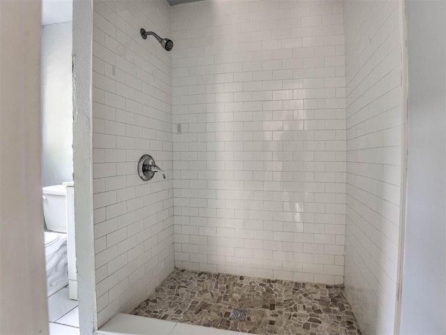 bathroom featuring tiled shower and toilet