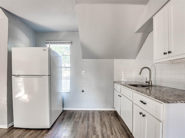 kitchen with light stone countertops, sink, white fridge, white cabinetry, and dark hardwood / wood-style floors