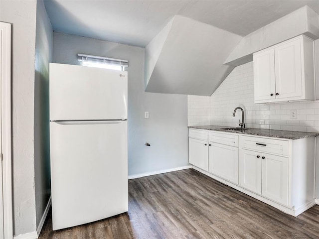 kitchen with dark stone counters, white cabinets, sink, dark hardwood / wood-style floors, and white fridge