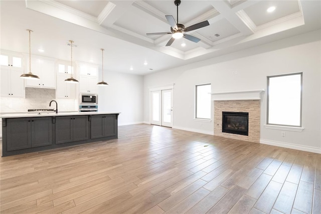 1817 Taines Turn, Norman, OK 73072 - unfurnished living room featuring a ceiling fan, coffered ceiling, light wood-style floors, baseboards, and beam ceiling