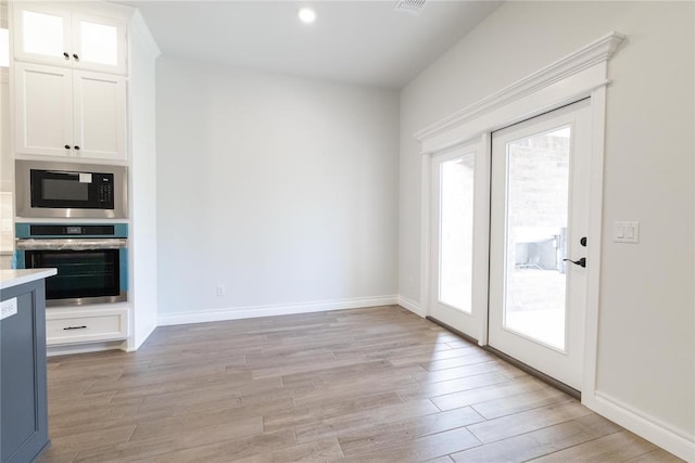 1817 Taines Turn, Norman, OK 73072 - kitchen with oven, built in microwave, white cabinets, light wood-type flooring, and light countertops