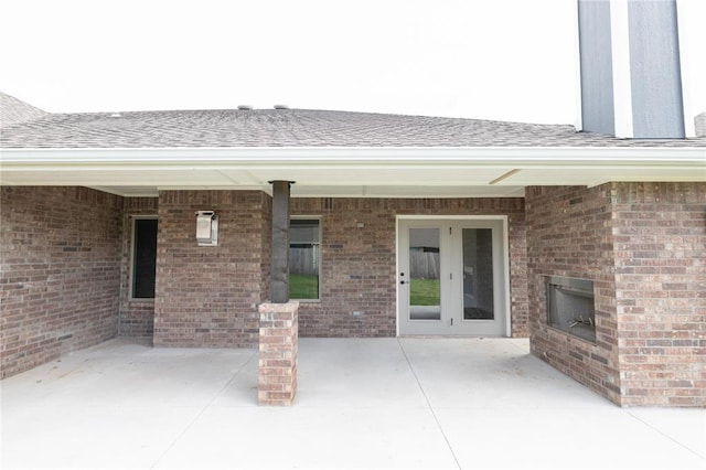 1817 Taines Turn, Norman, OK 73072 - entrance to property featuring a patio, a shingled roof, brick siding, and an outdoor brick fireplace