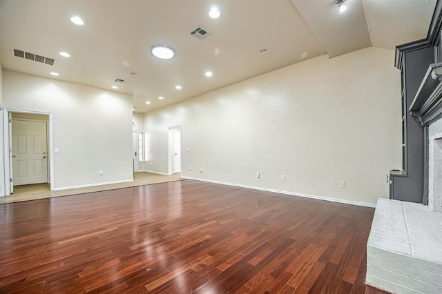 unfurnished living room with dark hardwood / wood-style flooring and a brick fireplace