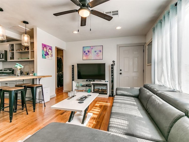 living room with light wood-type flooring and ceiling fan