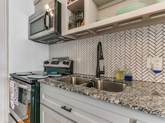 kitchen featuring stone counters, sink, tasteful backsplash, white cabinets, and appliances with stainless steel finishes