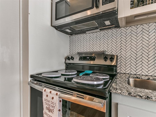 kitchen featuring tasteful backsplash, stone counters, white cabinetry, and stainless steel appliances