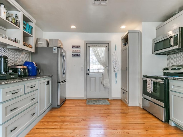 kitchen with tasteful backsplash, appliances with stainless steel finishes, and light hardwood / wood-style flooring