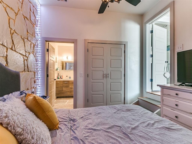 bedroom featuring a closet, ensuite bath, and ceiling fan