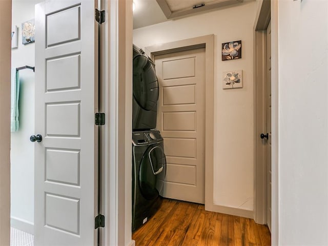 laundry area featuring stacked washer / drying machine and dark hardwood / wood-style floors