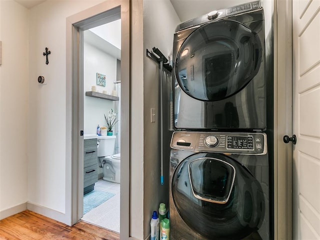 laundry area featuring wood-type flooring and stacked washing maching and dryer