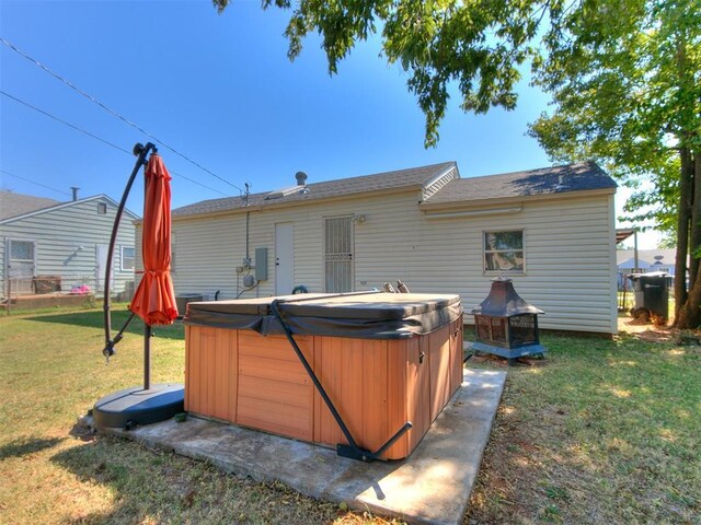 rear view of house with a yard and a hot tub