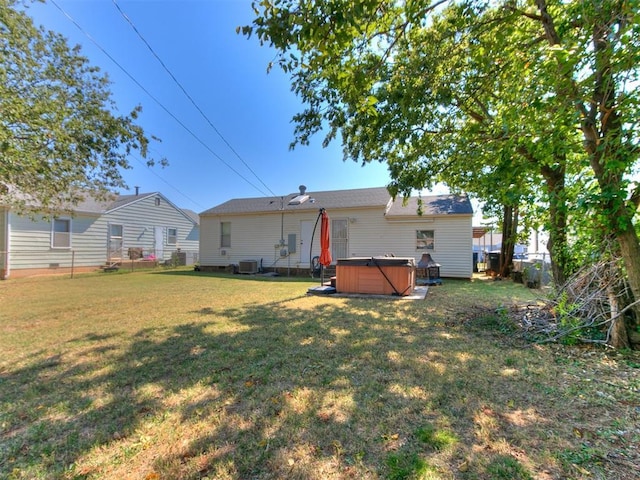 back of house with a lawn and a hot tub