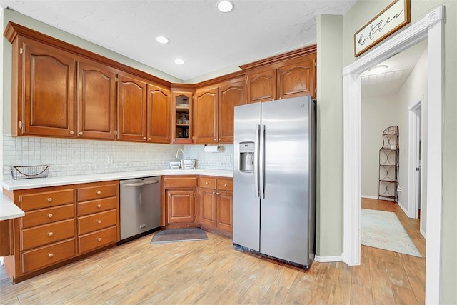 kitchen with tasteful backsplash, stainless steel appliances, and light hardwood / wood-style flooring