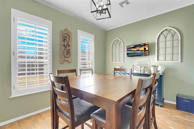 dining room with light wood-type flooring and crown molding