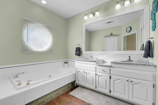 bathroom featuring tiled bath, hardwood / wood-style floors, and vanity