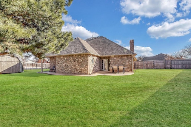 rear view of property featuring a lawn, a storage unit, and a patio area