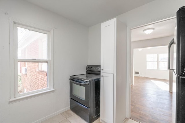 kitchen featuring stainless steel refrigerator, a wealth of natural light, electric range, and light hardwood / wood-style flooring