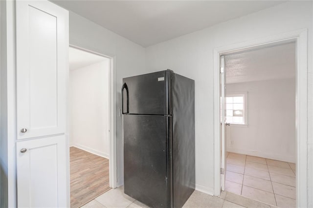 kitchen featuring white cabinets, light hardwood / wood-style flooring, and black fridge