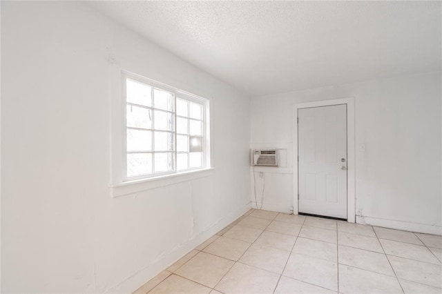 tiled empty room featuring a textured ceiling and a wall mounted AC