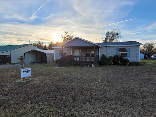 single story home featuring a porch, a yard, and a carport