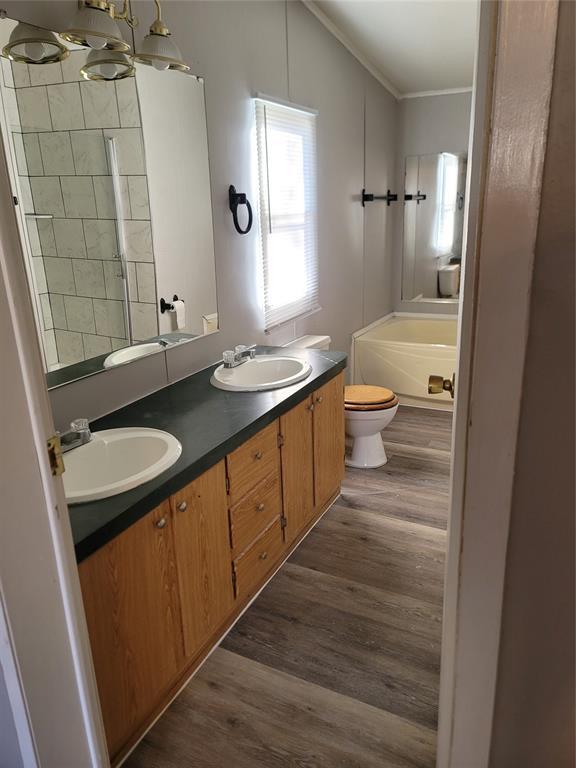 bathroom with ornamental molding, vanity, hardwood / wood-style floors, toilet, and lofted ceiling