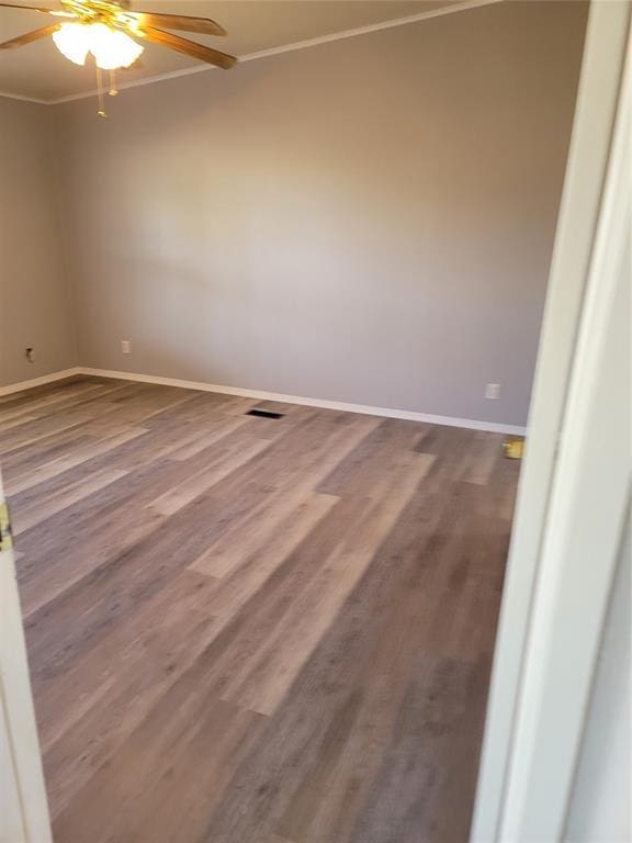 empty room featuring hardwood / wood-style flooring, ceiling fan, and crown molding