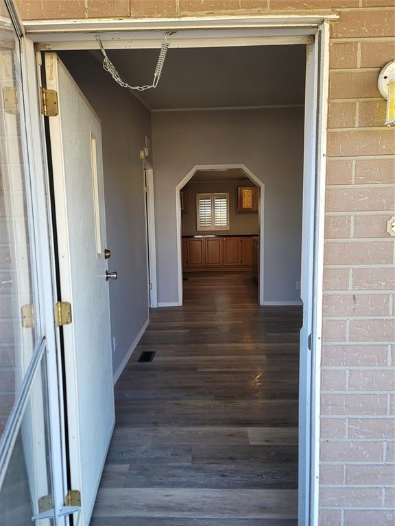 corridor with dark hardwood / wood-style flooring and brick wall