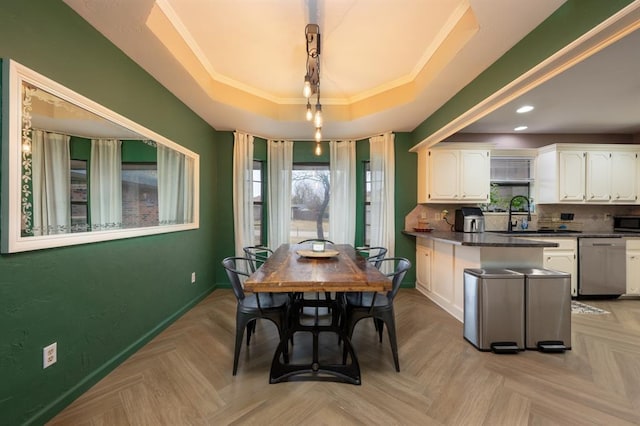 dining area featuring light parquet flooring, a tray ceiling, ornamental molding, and sink