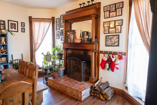 living area with a brick fireplace and hardwood / wood-style flooring