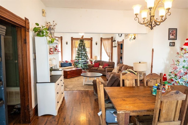 dining area with dark hardwood / wood-style floors and a notable chandelier