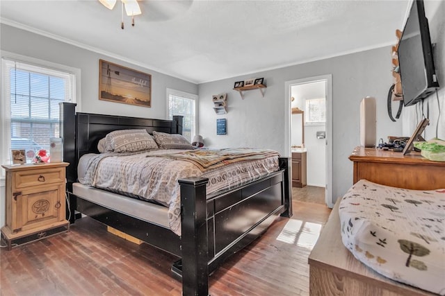 bedroom featuring dark hardwood / wood-style flooring, ensuite bath, multiple windows, and ceiling fan