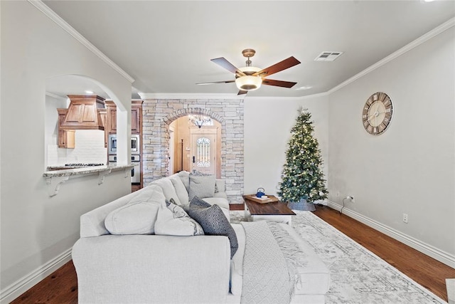 living room with ceiling fan, crown molding, and dark wood-type flooring