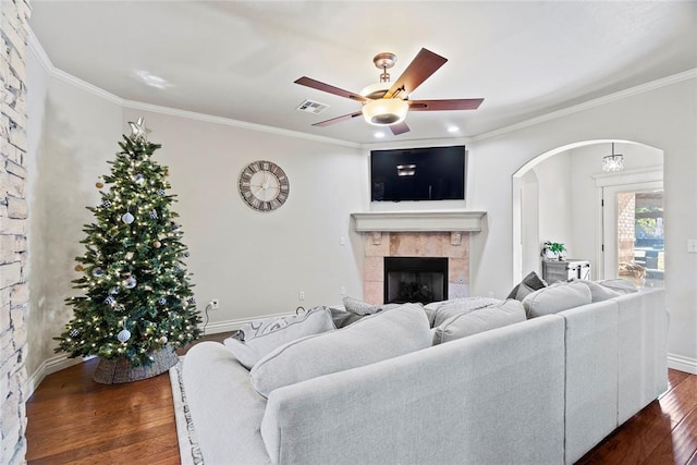 living room with a fireplace, ceiling fan, crown molding, and dark wood-type flooring