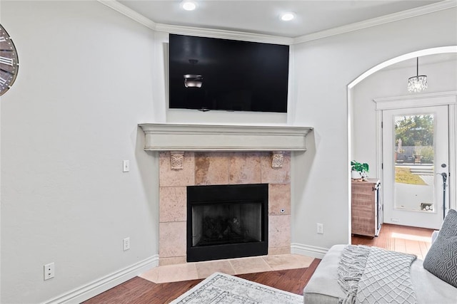 living room featuring a chandelier, a fireplace, ornamental molding, and hardwood / wood-style flooring