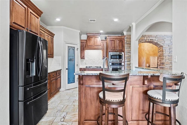 kitchen featuring backsplash, a kitchen breakfast bar, light stone counters, kitchen peninsula, and stainless steel appliances