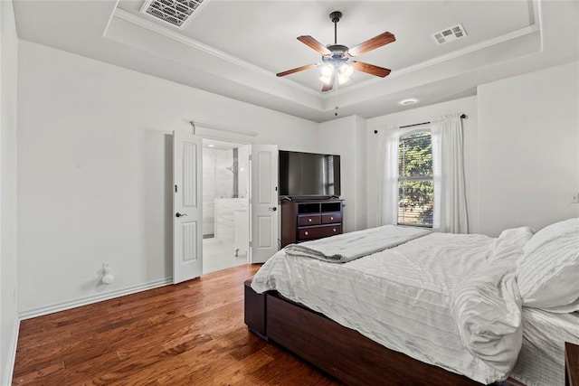 bedroom featuring ceiling fan, a raised ceiling, ensuite bathroom, hardwood / wood-style flooring, and ornamental molding