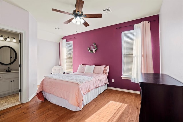 bedroom with ensuite bath, ceiling fan, sink, and hardwood / wood-style flooring