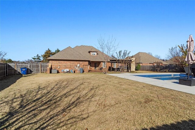 back of house with a lawn, a patio area, central AC, and a covered pool