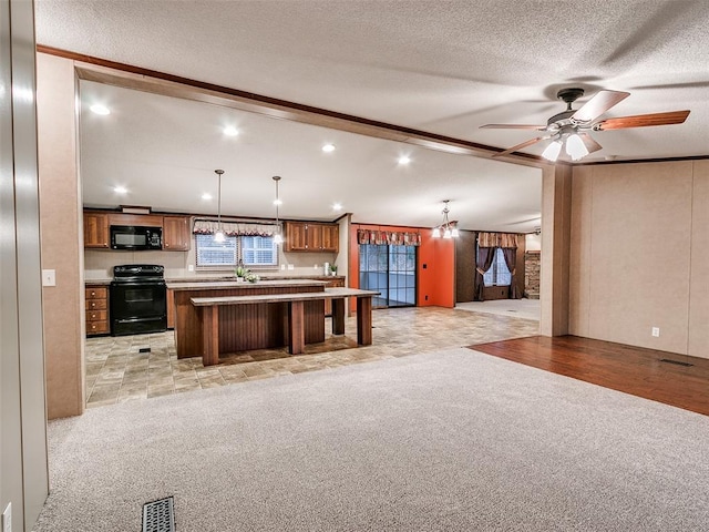 kitchen with black appliances, a center island, hanging light fixtures, and a textured ceiling